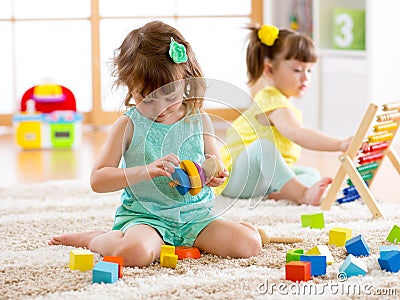 Children toddler and preschooler girls play logical toy learning shapes, arithmetic and colors at home or nursery Stock Photo