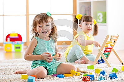 Children toddler and preschooler girls play logical toy learning shapes, arithmetic and colors in kindergarten or Stock Photo