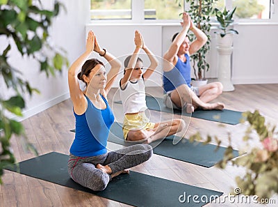 Children together with parents in yoga pose agni stambhasana Stock Photo