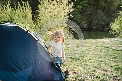 Children tourism. Happy kid girl in a campaign in a tent. Family summer vacation in nature Stock Photo