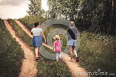 Children walking on rural road uphill towards dramatic sky on horizon in countryside concept happy childhood lifestyle Stock Photo