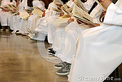 Children wihite white tunics of first communion at mass Stock Photo