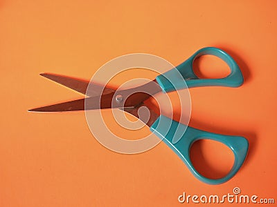 Children's blue scissors on orange background. Stock Photo