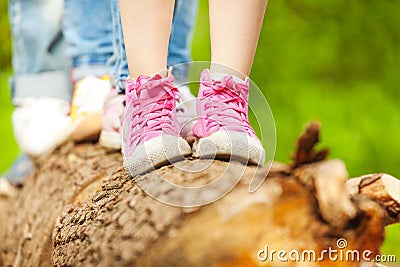 Children's feet in pink sneakers standing on a log Stock Photo