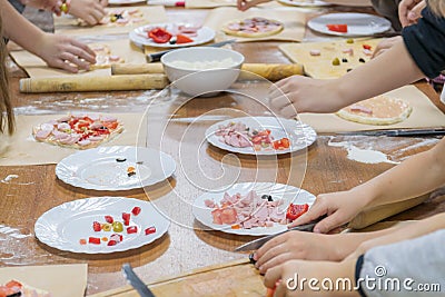 Children& x27;s hands are cutting food for making their first pizza on wooden table. Cooking master class Stock Photo