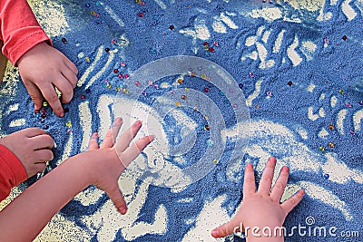 Childrens hands touching blue sand on white table sand therapy, development of fine motor skills Stock Photo