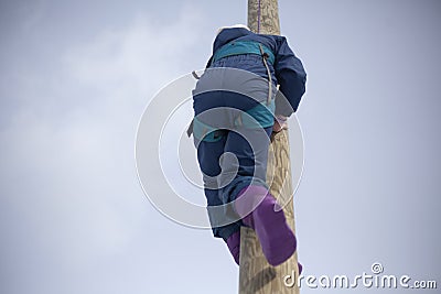 Childrens mountain climbing. A girl climbs on a pole. A child with insurance climbs a tall pole. Stock Photo