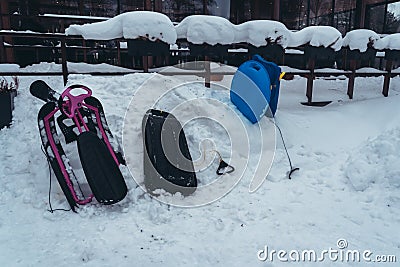Childrens plastic sledges waiting outside a cafe in the snow Stock Photo
