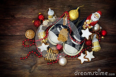 Childrens shoes filled with sweets and red christmas decoration Stock Photo