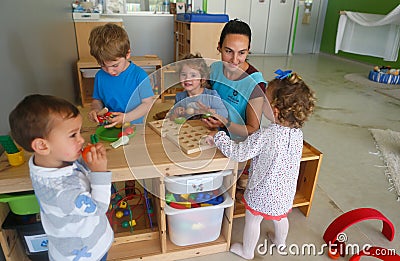 Childrens and their teacher at Kindergarten in classroom Editorial Stock Photo