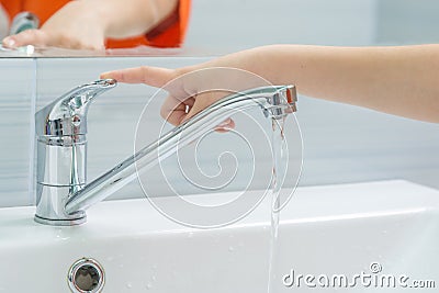 The childs hand closes the water from the mixer by pressing the finger on the handle Stock Photo