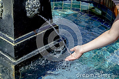 A childs hand recieving water from a lion head water fountain. Editorial Stock Photo