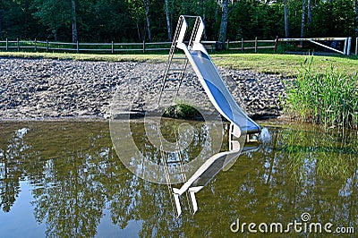 childs slide mirroring in calm water at beach Stock Photo