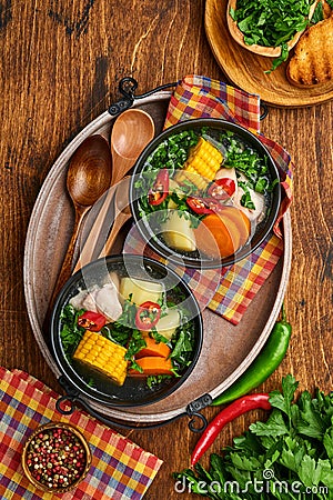 Chilean meat soup with pampkin, corn, fresh coriander and potatoes on old wooden table background. Cazuela. Latinamerican food Stock Photo