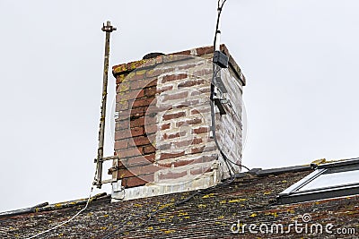 Chimney stack on a house roof, partly weather sealed and repaired with a recent repointing of its mortar cement Stock Photo