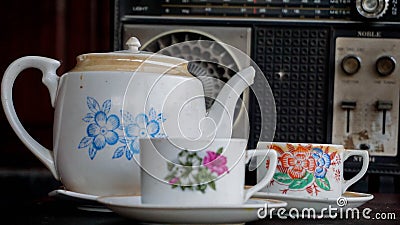 China porcelain teapot with flower pattern and white glass with radio classic background on the old house Stock Photo