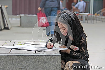 China, Suzhou - April 14, 2012. A Chinese girl draws in a book or paints pictures Editorial Stock Photo