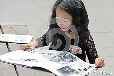 China, Suzhou - April 14, 2012. A Chinese girl draws in a book or paints pictures Editorial Stock Photo