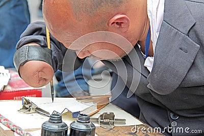 China, Suzhou - April 14, 2012. A man with a disabled person writes calligraphy, Chinese characters on the fan, sneers for Editorial Stock Photo