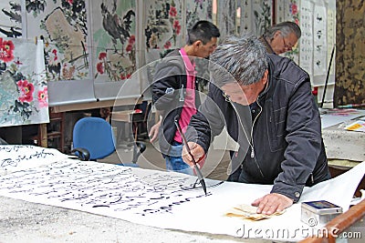 China, Suzhou - April 14, 2012. The man writes Chinese characters with a brush, calligraphy in China. The man is Chinese Editorial Stock Photo