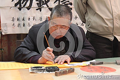 China, Suzhou - April 14, 2012. The man writes Chinese characters with a brush, calligraphy in China. The man is Chinese Editorial Stock Photo