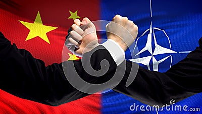 China vs NATO confrontation, countries disagreement, fists on flag background Editorial Stock Photo