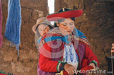 CHINCHERO, PERU- JUNE 3, 2013: Native Cusquena woman dressed in traditional colorful clothing explaining the dyeing threads and we Editorial Stock Photo