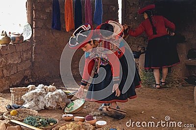 CHINCHERO, PERU- JUNE 3, 2013: Native Cusquena woman dressed in traditional colorful clothing explaining the dyeing threads and we Editorial Stock Photo