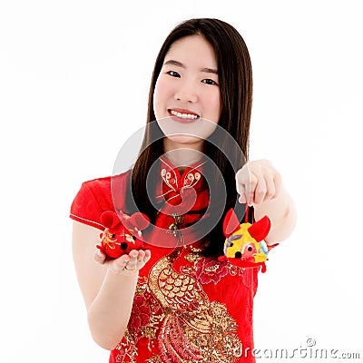 Chinese beautiful woman smiling in red dress is showing a red doll on her right hand and a yellow doll on her left hand to a Stock Photo