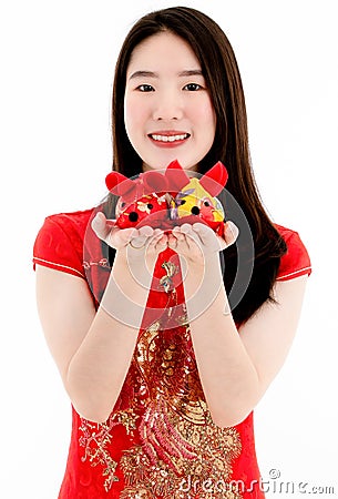 Chinese beautiful woman smiling in red dress is showing a red doll on her right hand and a yellow doll on her left hand to a Stock Photo