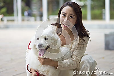 Asian beauty embracing her dog smiling at camera outdoor in garden Stock Photo
