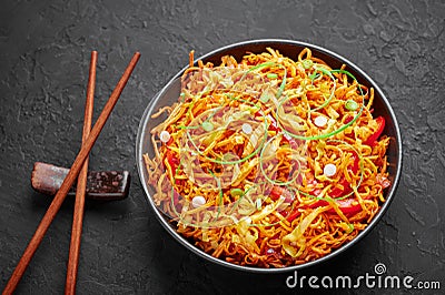 Chinese Bhel in black bowl on dark slate table top. Indo-Chinese cuisine street food dish with schezwan sauce Stock Photo