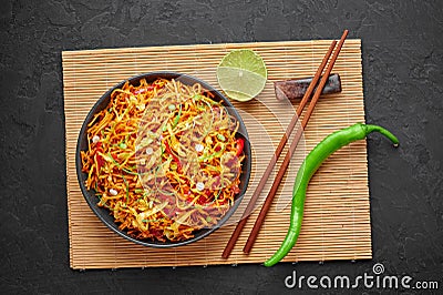 Chinese Bhel in black bowl on dark slate table top. Indo-Chinese cuisine street food dish with schezwan sauce Stock Photo