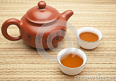 Chinese clay tea pot with two cups of tea on a straw mat. Transl Stock Photo