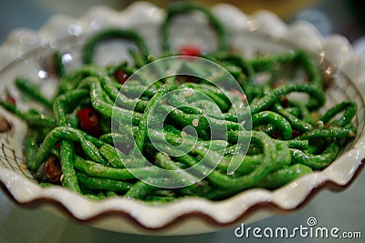 A traditional Chinese dish of green string beans with red chili pepper, served in a white plate. Beijing, China. Stock Photo