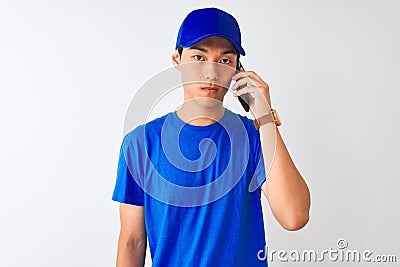 Chinese deliveryman wearing cap talking on the smartphone over isolated white background with a confident expression on smart face Stock Photo