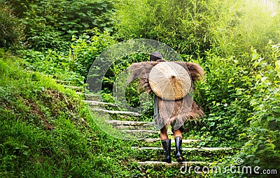 Chinese farmer in antique raincoat walking up stairs Editorial Stock Photo