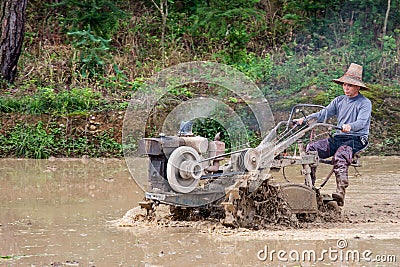 Chinese farmer working in rice field with a motorized plow Editorial Stock Photo