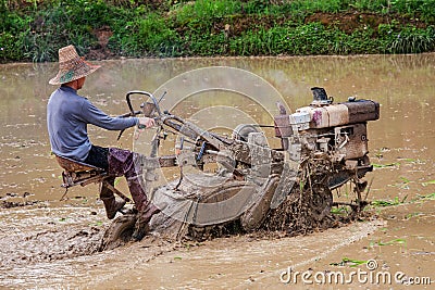 Chinese farmer working in rice field with a motorized plow Editorial Stock Photo