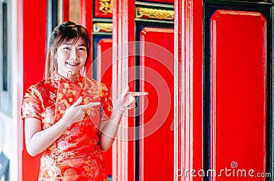Chinese girl in traditional Chinese cheongsam pointing at china temple and introduce something to you Stock Photo