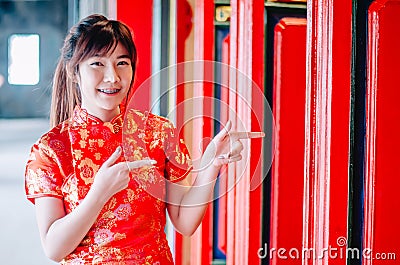 Chinese girl in traditional Chinese cheongsam pointing at china temple and introduce something to you Stock Photo