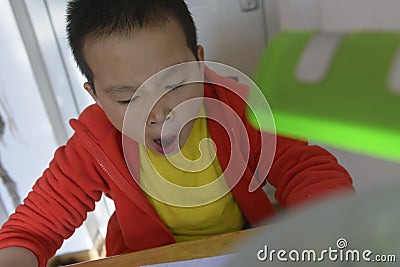 Chinese kid yawn doing homework Stock Photo