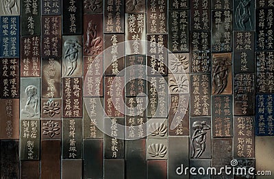 Chinese lettering teachings and Carved buddha images into a slab of colored tiles on temple wall Stock Photo