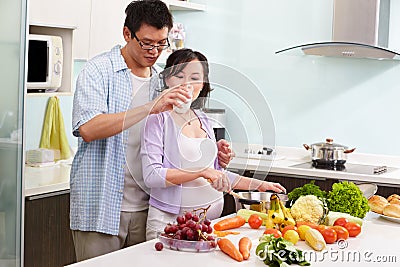 Chinese man giving milk to her pregnant wife Stock Photo