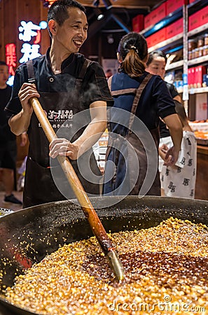 Chinese man mixing food in a huge wok Editorial Stock Photo