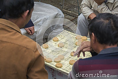 Chinese men playing `Xiangqi`, also known as `Chinese Chess`, a popular strategy board game Editorial Stock Photo