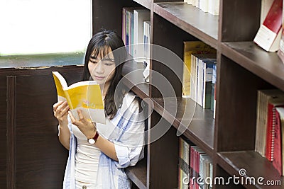 Chinese Portrait of young beautiful woman reads Book In Bookstore Stock Photo