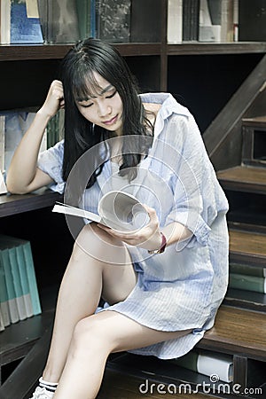 Chinese Portrait of young beautiful woman reads Book In Bookstore Stock Photo