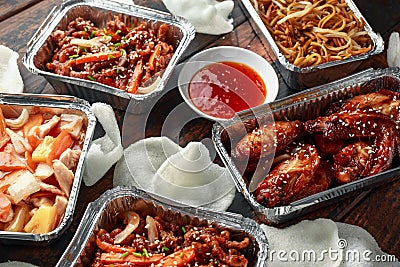Chinese takeaway food. Crispy shredded beef, sweet and sour chicken wings, egg noodles with bean sprouts, pineapple Stock Photo