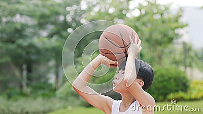 Teenage Asian boy playing basketball outdoors preparing for shooting Stock Photo